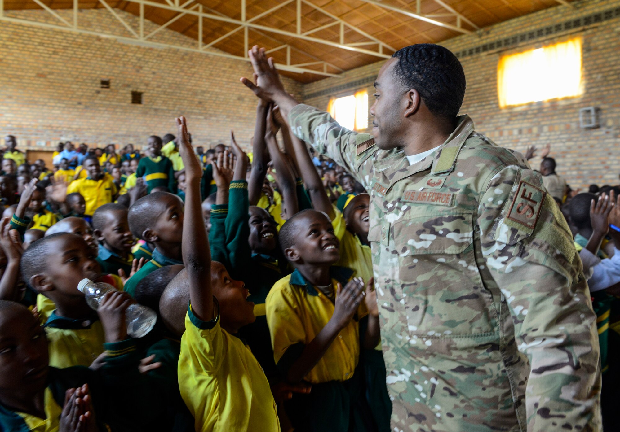 U.S. Air Force Master Sgt. Julius Stokes, Air Force Installation and Mission Support Center Detachment 4, high-fives students of the Home de la vierge des Pauvres Gatagara/Nyanza in the Nyanza District, Rwanda, March 5, 2019. Stokes traveled to HVP Nyanza with the U.S. Air Forces in Europe Band as part of an outreach event. (U.S. Air Force photo by Tech. Sgt. Timothy Moore)