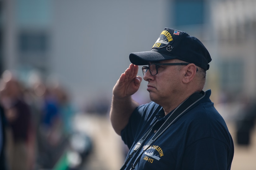 A crewmember from the USS Charleston (LKA-113), an amphibious Navy cargo ship commissioned in 1968, salutes during the new USS Charleston (LCS-18) commissioning ceremony March 2, 2019, in Charleston, S.C.