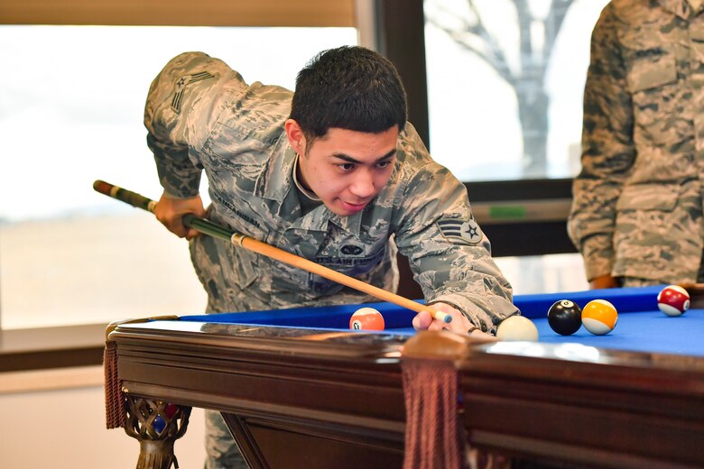 Senior Airman Anthony Panganiban, 50th Security Forces response force member, plays pool during the First Friday at the event center, Schriever Air Force Base, Colorado, March 1, 2019. First Friday is a morale boosting event held every month to give Schriever Airmen an opportunity to relax and connect in a less formal setting. (U.S. Air Force photo by Katie Calvert)
