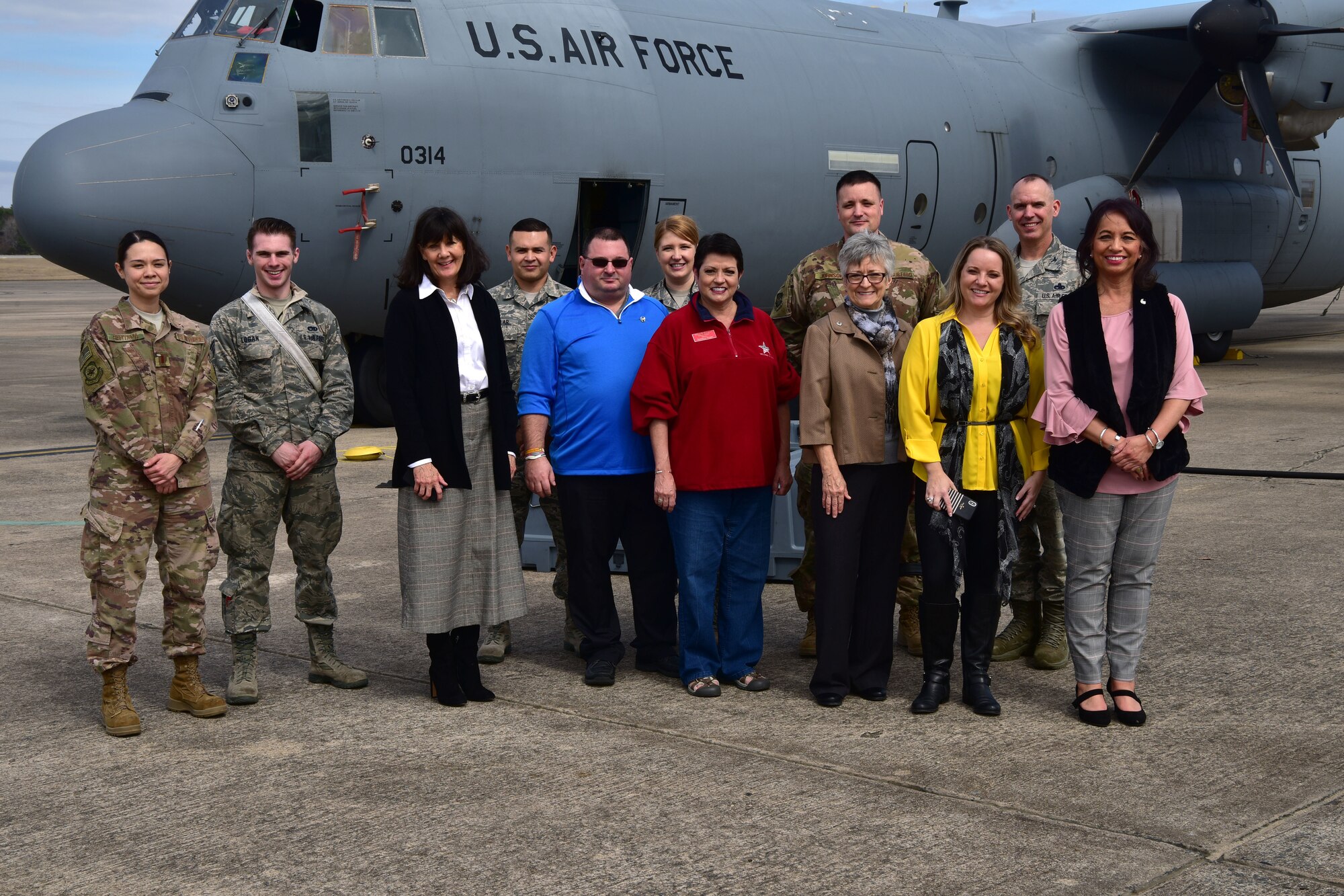 Honorary commanders pose for a photo in fron of a C-130J.