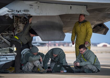 U.S. Air Force Airmen from the 1st Aircraft Maintenance Squadron check technical orders under an F-22 Raptor during a total force exercise at Joint Base Langley-Eustis, Virginia, Feb. 28, 2019.