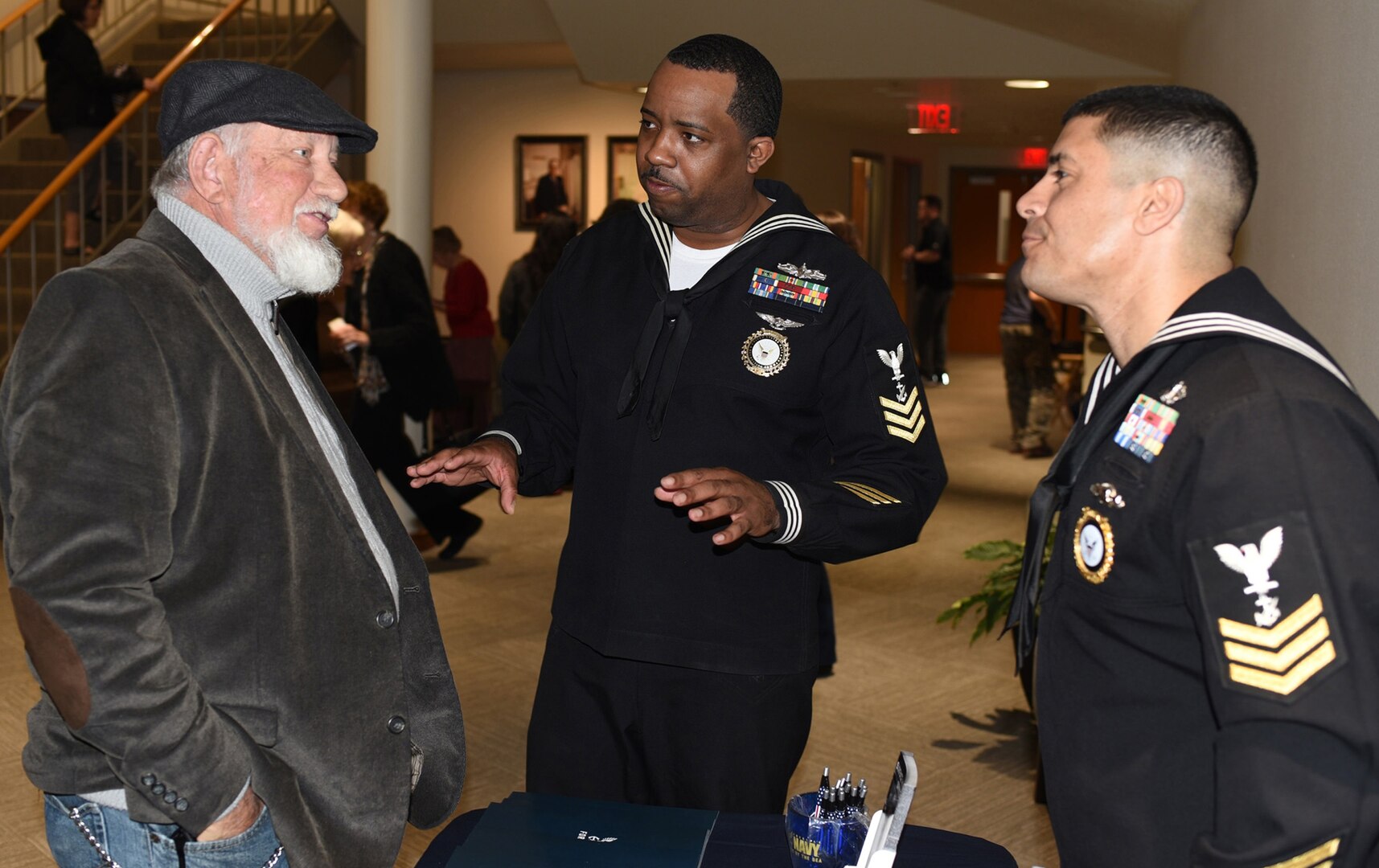 Petty Officer 1st Class Harold Dayse (center), the leading petty officer assigned to Navy Recruiting Station New Braunfels, joined by Petty Officer 1st Class Jose Zouain (left), assigned to NRS San Marcos, speaks with a veteran during the U.S. Navy Band concert held in the Jackson Auditorium on the campus of Texas Lutheran University.  The U.S. Navy Band performed in 10 states during its 23-city, 5,000-mile tour, connecting communities across the nation to their Navy. The tour serves audiences with entertaining performances but also allows America’s Navy direct access to both former and future members of the Navy.