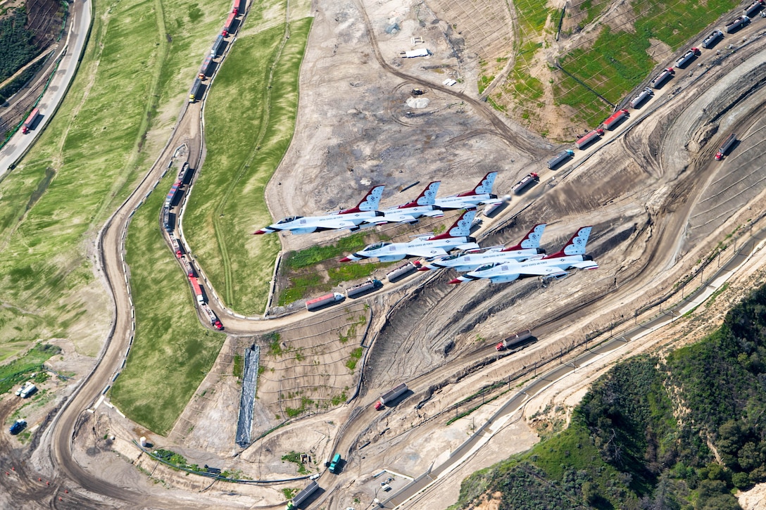 A group of aircraft fly over terrain in Los Angeles.