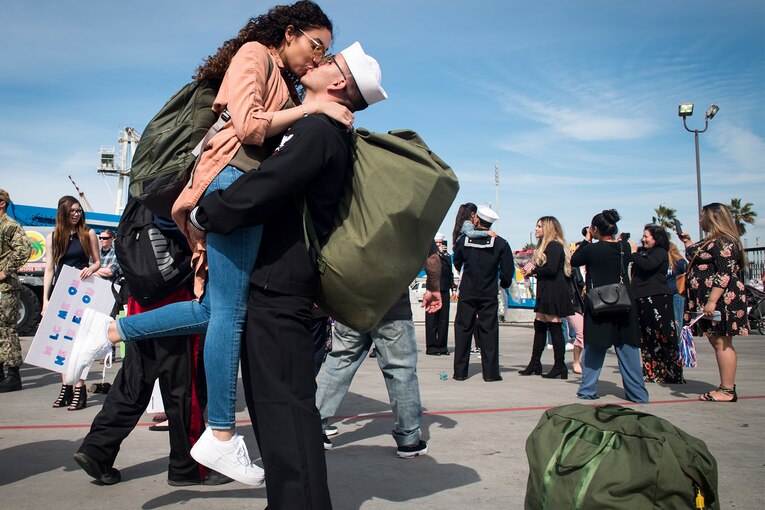 A service member kisses his wife at a homecoming event.