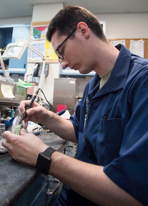 Senior Airman Nicholas Carter, 15th Aerospace Medicine Squadron dental lab technician, cuts a mouth guard away from its mold on Joint Base Pearl Harbor-Hickam, Hawaii, March 4, 2019. A mouth guard is a piece of soft plastic that protects the lips, cheeks, tongue, teeth and the jaw, absorbing the force of impact from another object before the force reaches the teeth. (U.S. Air Force photo by Tech. Sgt. Heather Redman)