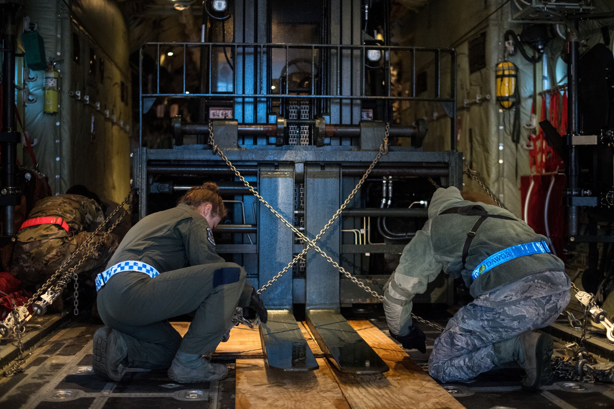 U.S. Air Force Airmen assigned to the 37th Airlift Squadron, 721st Aerial Port Squadron, and the 86th Logistics Readiness Squadron, chain down a 10k standard to a C-130J Super Hercules on the flightline at Ramstein Air Base, Germany, March 1, 2019. After they finished, the team loaded a pallet of cargo onto the aircraft as part of a week-long exercise in conjunction with Operation Varsity, a wing commander initiative designed to enhance contingency capabilities. (U.S. Air Force photo by Staff Sgt. Devin Boyer)