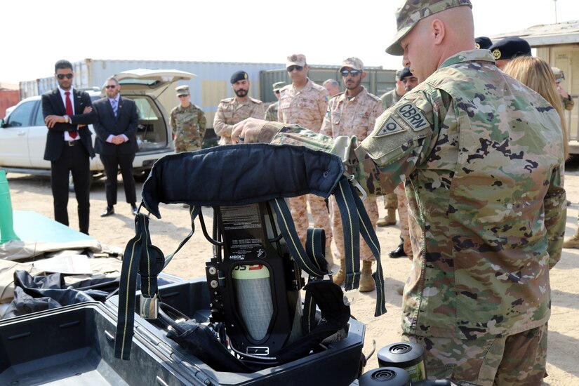 Staff Sgt. Dustin Bowshier of the 637th chemical, biological, radiological and nuclear Company is the Non-Commissioned Officer in Charge and explains the self-contained breathing apparatus that is worn with the suits for different levels of contamination during the display on the CBRN dismounted reconnaissance equipment on Feb. 14, 2019 at Camp Arifjan, Kuwait. Soldiers from the unit provide a display of layout and equipment with CBRN dismounted reconnaissance equipment to Kuwait Weapons of Mass Destruction Defense Command. The 637th Chemical Company is deployed to Kuwait as the CBRN defense response force for the U.S. Central Command area of responsibility.