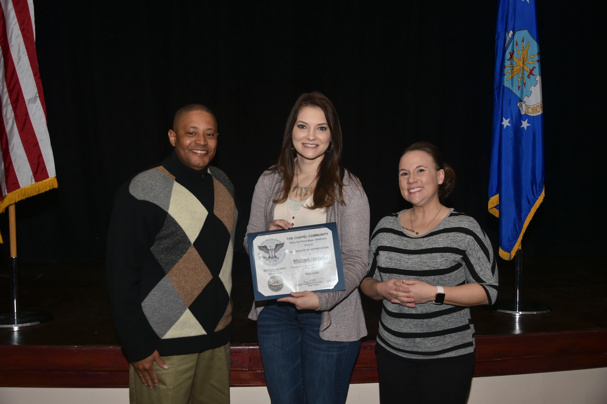 Jill Hodges, the wife of U.S. Air Force Staff Sgt. Michael Hodges, a defense paralegal assigned to the 97th Air Mobility Wing, accepts the Silver-Level Presidential Volunteer Service Award on his behalf, March 2, 2019, at Altus Air Force Base, Okla. (U.S. Air Force photo by Senior Airman Cody Dowell)