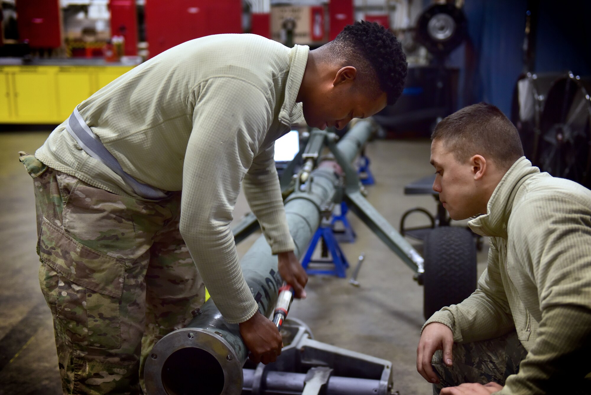 Two men look over a piece of equipment.