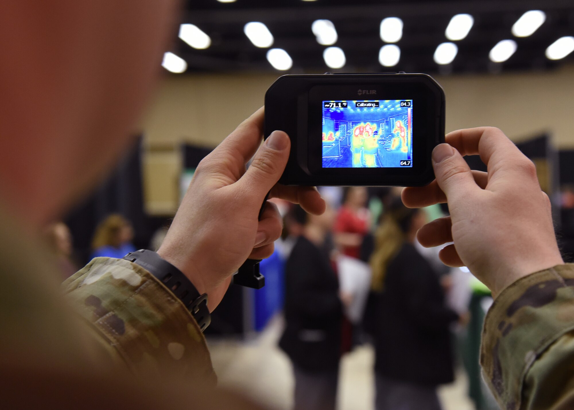 U.S Air Force Staff Sgt. Benjamin Myers, 315th Training Squadron instructor displays the functionality of a forward looking infrared camera while setting up a booth while attending Careers Y’all, a youth career fair, at the McNease Convention Center, in San Angelo, Texas, March 6, 2019. The cameras produce imagery based on thermal activity and can be attached to remotely piloted aircrafts for aerial assessments. (U.S. Air Force photo by Airman 1st Class Abbey Rieves/Released)