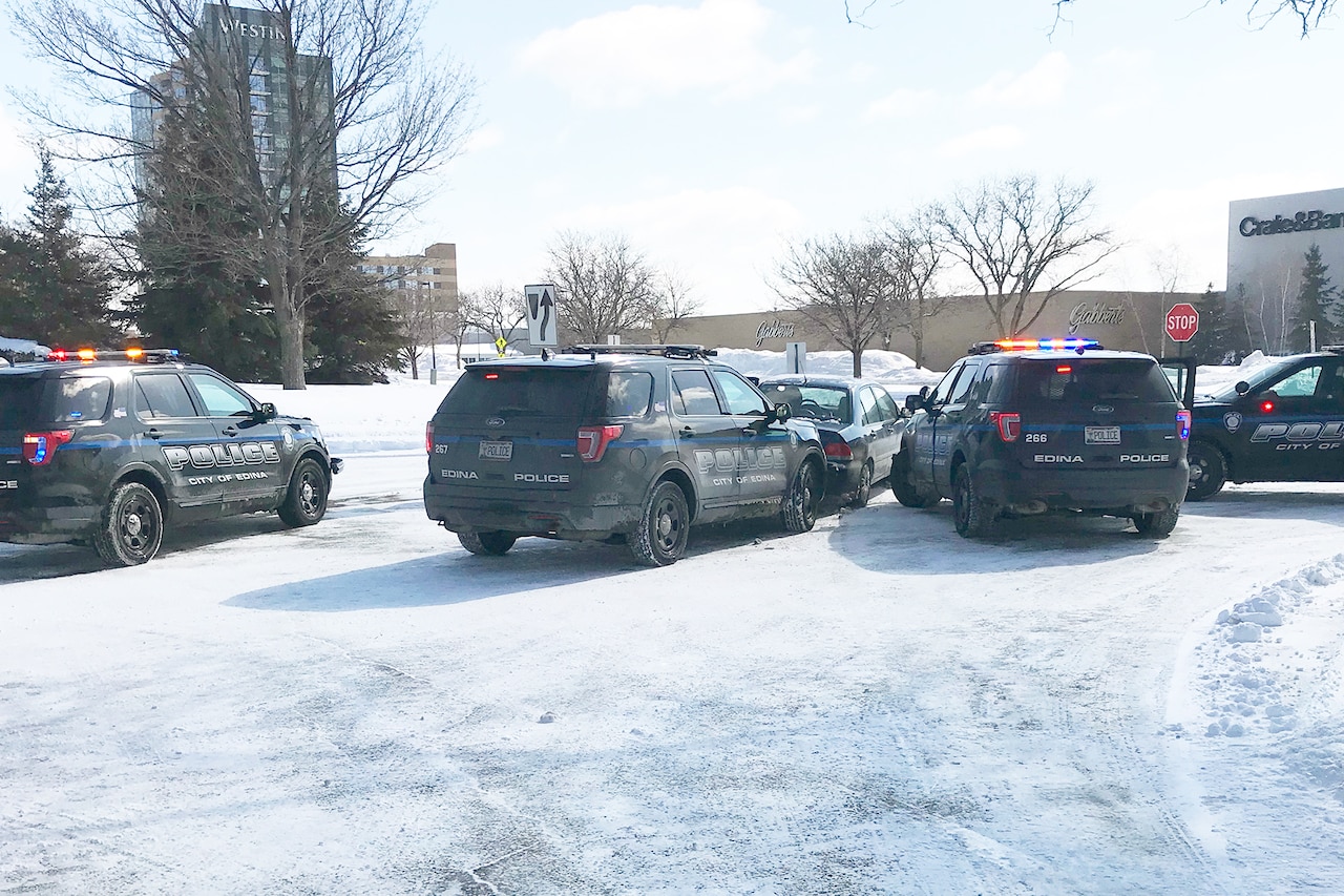 Police vehicles surround a civilian vehicle