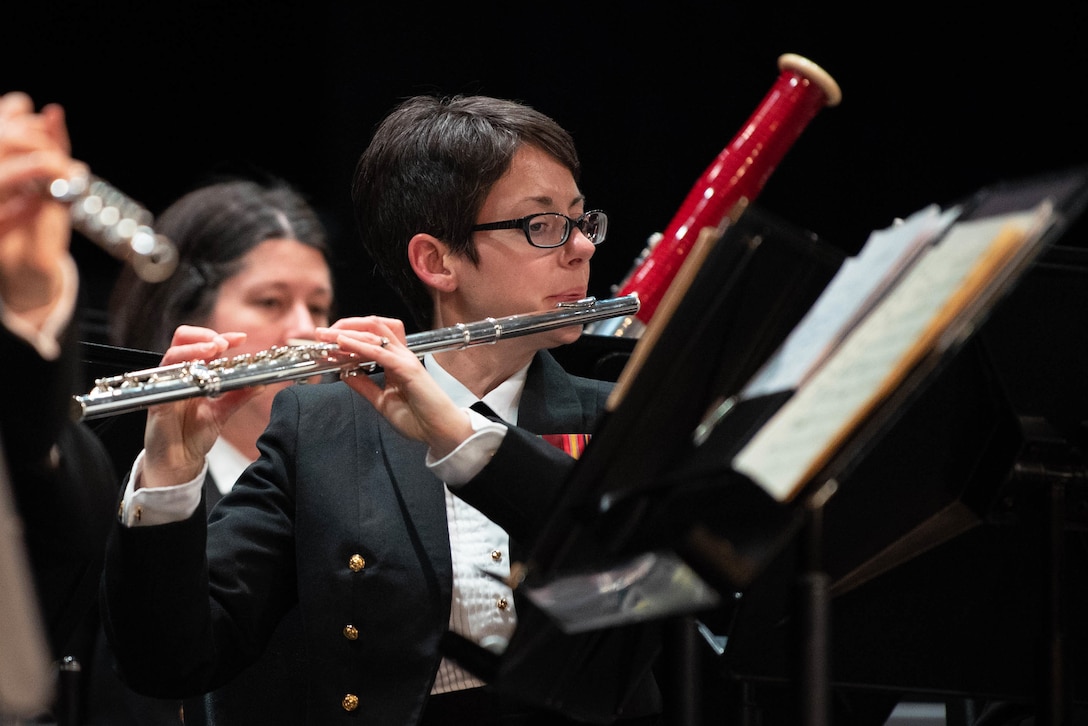 A sailor plays flute with a band.