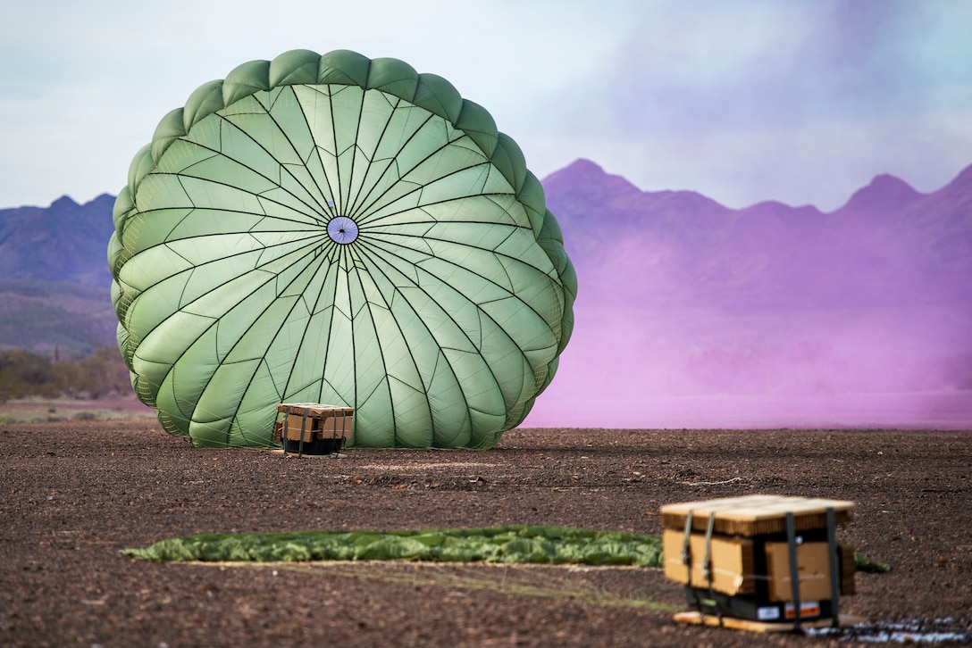 A parachute lands on the ground with a trunk.