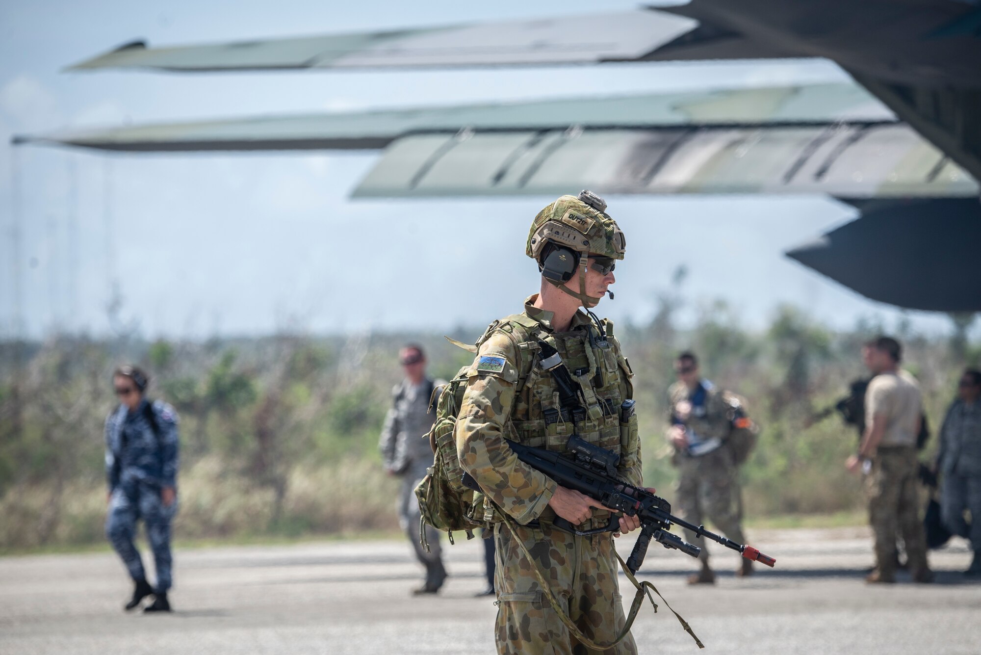 A Royal Australian air force member provides security for passengers exiting a plane during exercise Cope North at Tinian, U.S. Commonwealth of the Northern Marianas Islands stands, Feb. 19, 2019.