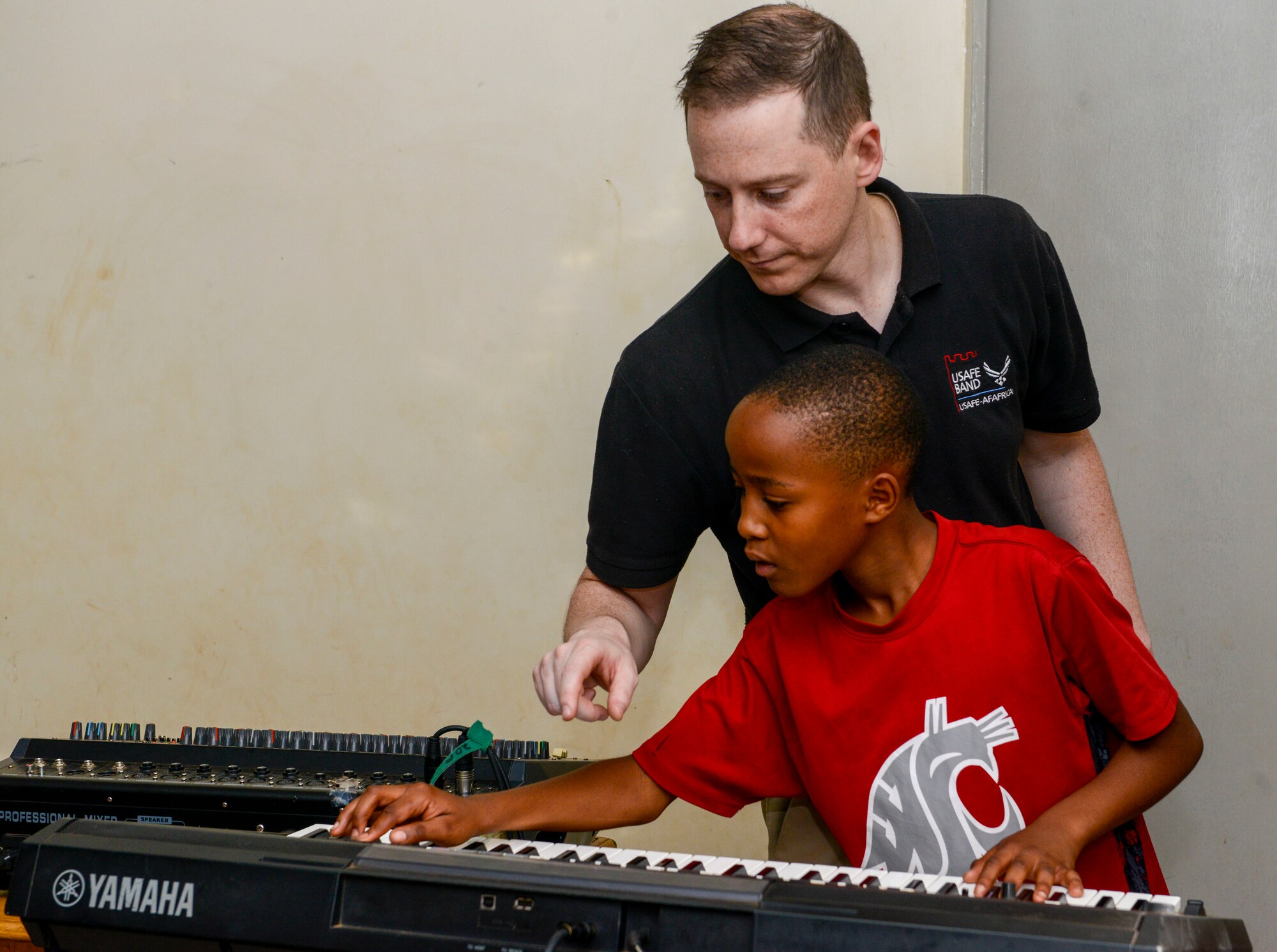 U.S. Air Force Staff Sgt. Justin Cockerham, U.S. Air Forces in Europe Band pianist, helps a student with find the right notes on a keyboard at the Gisimba Memorial Centre in Kigali, Rwanda, March 6, 2019. As musical ambassadors, members of the band can reach audiences that traditional military members can't. They travel the world to build cultural bridges, and honor and preserve cultural heritage. (U.S. Air Force photo by Tech. Sgt. Timothy Moore)