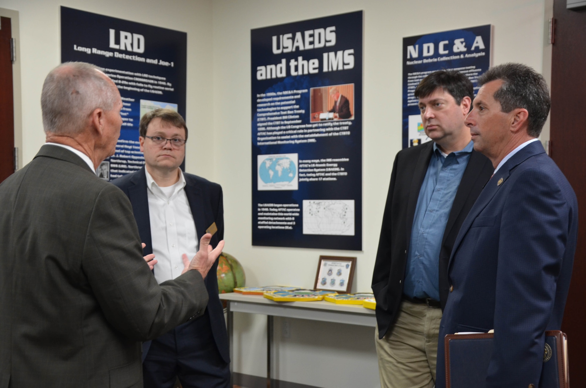 Mr. Jim Whidden, director of staff for the Air Force Technical Applications Center, briefs staff members from Rep. Bill Posey's (FL-8) office in AFTAC's Heritage Room at Patrick Air Force Base, Florida.  The staffers visited the nuclear treaty monitoring center March 4, 2019 to learn more about AFTAC's heritage and global mission.  Pictured from left to right: Whidden; Stuart Burns, chief of staff; Rick Podliska, senior policy advisor; and Patrick Gavin, district director.  (U.S. Air Force photo by Susan A. Romano)