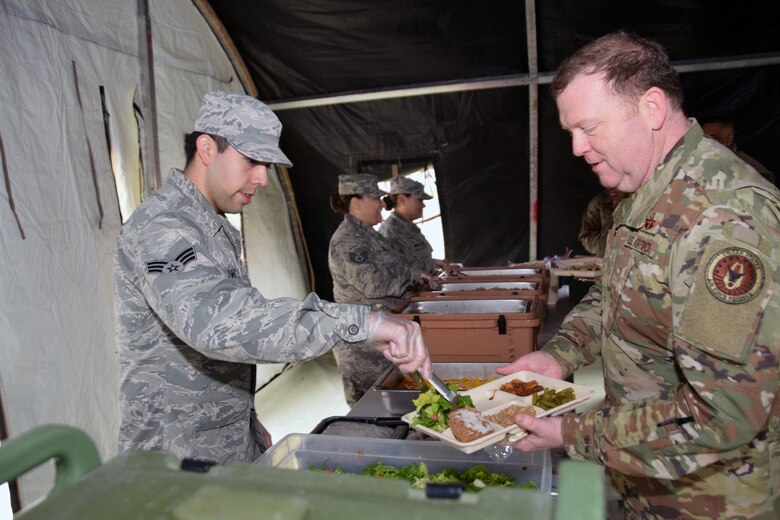 Senior Airman Jacob Livar, 433rd Force Support Squadron fitness specialist, serves a meal to Lt. Gen. Richard Scobee, commander of the Air Force Reserve Command, March 2, 2019 at Joint Base San Antonio-Lackland, Texas.