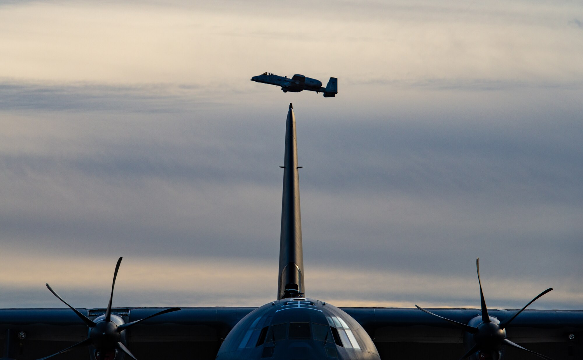 An A-10C Thunderbolt II flies over a C-130 J Hercules