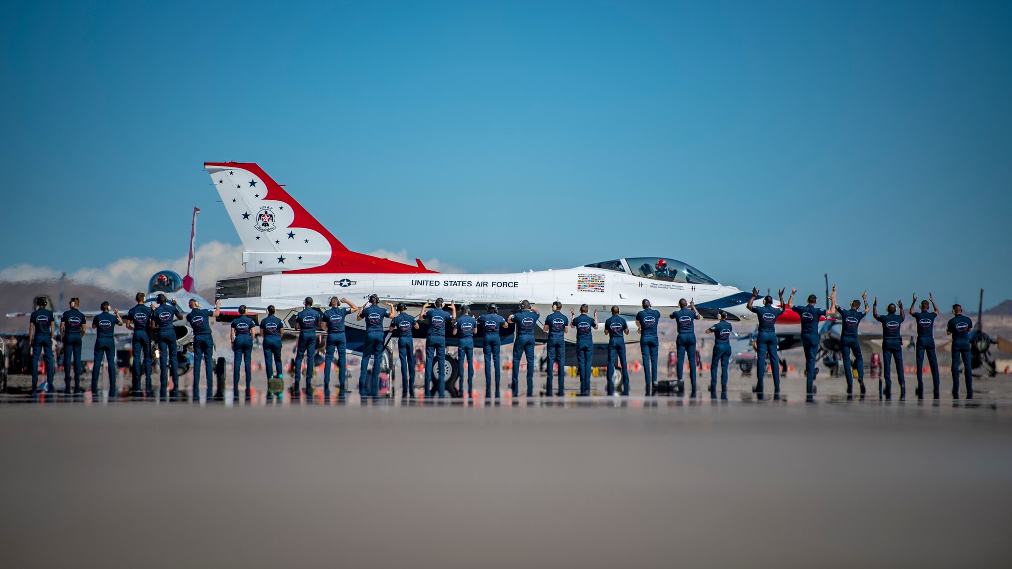 Thunderbird pilots stand on a flightine in front of a plane