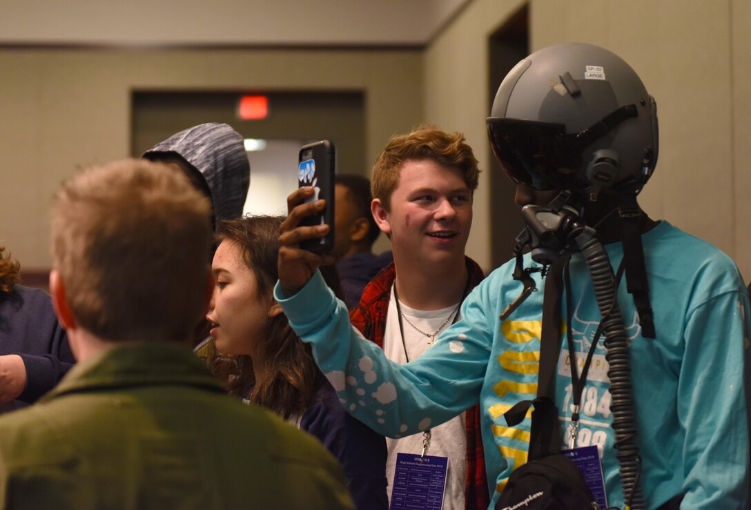 A high school student takes a photo while wearing a pilot helmet training at Mississippi State University’s Engineering Day March 4, 2019, in Starkville, Mississippi. In addition to the VR technology, the pilots also taught the class about G-suits, pilot helmets and parachute harnesses; some of the gear necessary to fly in an Air Force aircraft. (U.S. Air Force photo by Senior Airman Beaux Hebert)