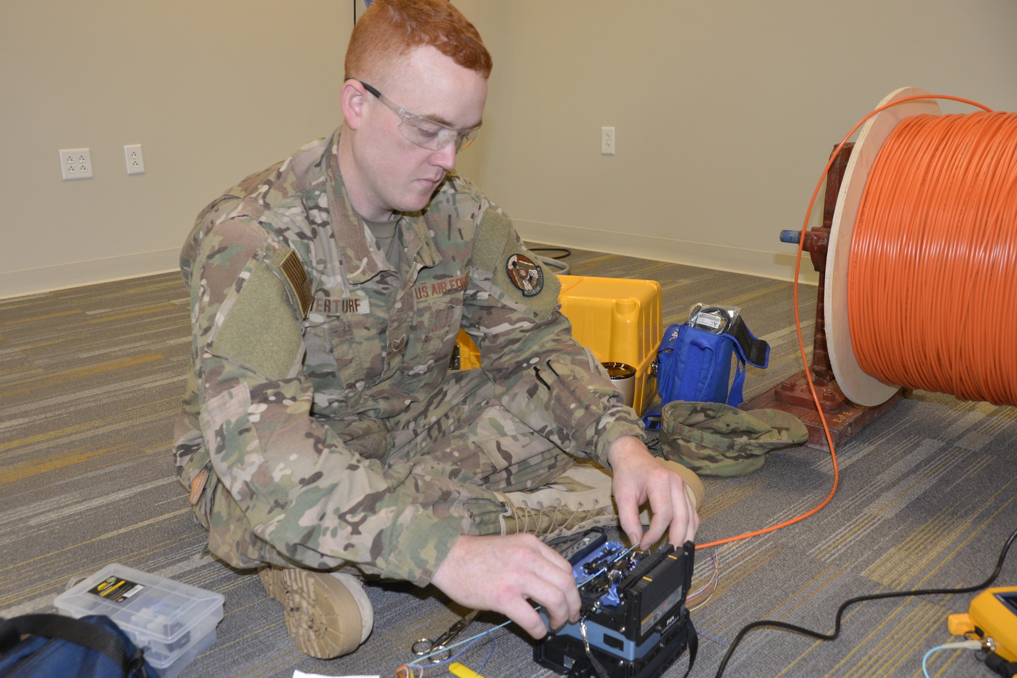 Staff Sgt. Jeremy Overturf, cable and antenna maintenance specialist with the 241st Engineering Installation Squadron, Chattanooga, Tenn., uses a fusion splicer to check new fiber optic cable prior to installation in a 1st Air Force (Air Forces Northern) Headquarters building office. Overturf is part of a group of seven Airmen from the 241st EIS who deployed here to assist the 1st AF (AFNORTH) enterprise to restore its communications and computer capabilities following the devastating effects of Hurricane Michael Oct. 10, 2018. (Air Force photo by Mary McHale)