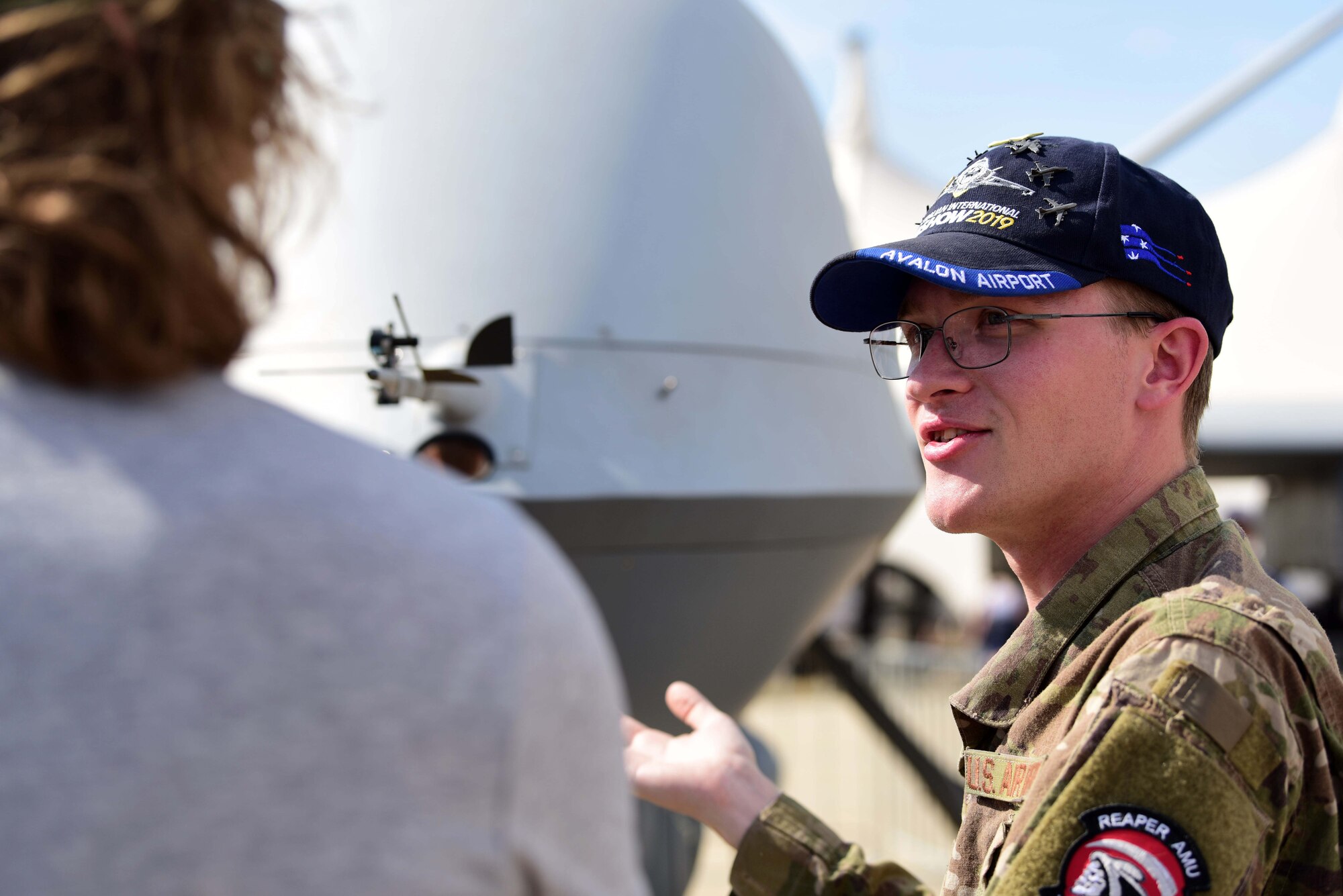 Staff Sgt. Dylan, MQ-9 Reaper avionics craftsman, explains the effects of taking the cockpit out of the aircraft to an airshow attendee during the Australian International Airshow, Mar. 3, 2019, in Geelong, Victoria, Australia. Over the week, the crews met with many of the airshow’s more that 200,000 visitors and aviation fans. (U.S. Air Force photo by Airman 1st Class Haley Stevens)