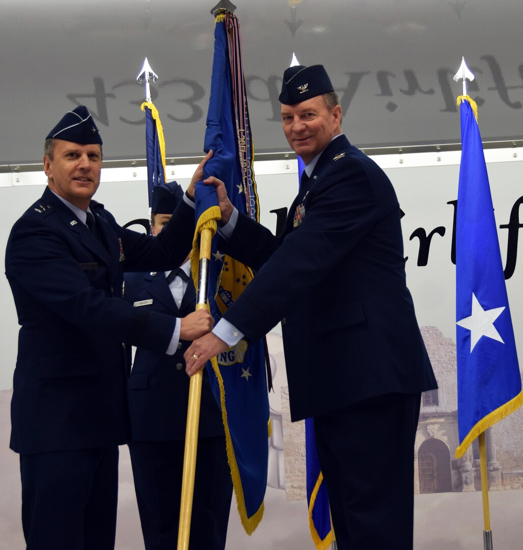 Maj. Gen. Randall A. Ogden, 4th Air Force commander, presents the wing guidon to Col. Terry W. McClain, 433rd Airlift Wing commander, at the 433rd AW change of command ceremony March 3 at Joint Base San Antonio-Lackland.