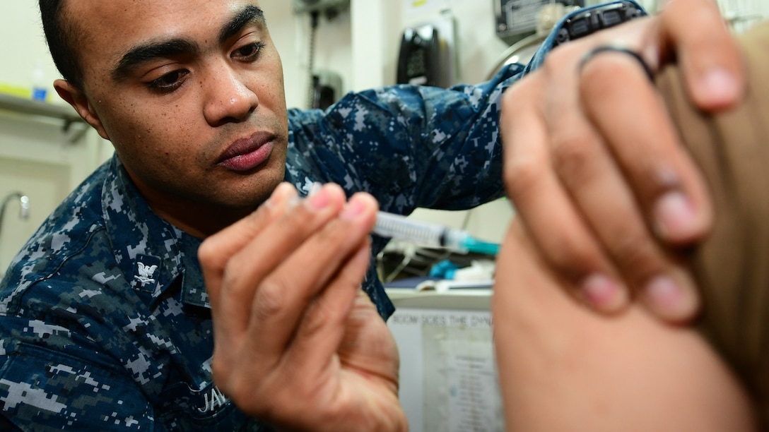 Hospital Corpsman 3rd Class Fernando Javier administers a typhoid shot to a patient in a medical room aboard the Nimitz-class aircraft carrier USS Harry S. Truman (CVN 75).