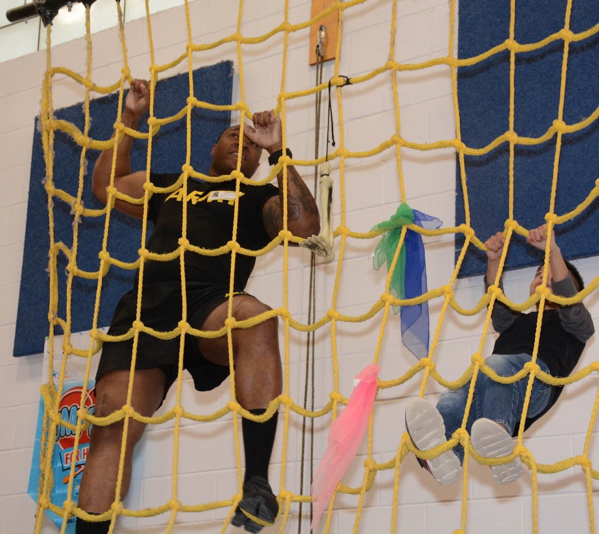 A Soldier leads a student on the cargo climbing net. A group of Soldiers and Sailors joined Colonial Hills Elementary School students at their Heroes for Health Day Feb. 28.