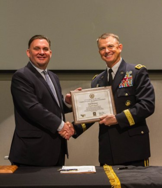 III Corps and Fort Hood Commanding General, Lt. Gen. Paul E. Funk II, presents Halliburton's Chief of Human Resources and Executive VP of Administration, Lawrence Pope, with an award on behalf of the Partnership for Youth Success program. Soldiers, leaders and community members attended a ceremony at Halliburton's corporate headquarters as they join forces with the PaYS program Feb. 27.