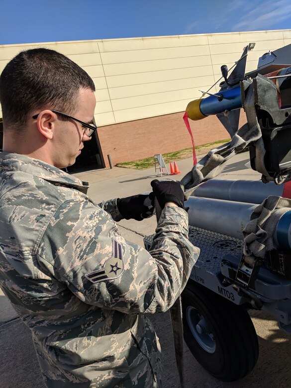 A1C Dylan Dodd secures bombs to a bomb rack