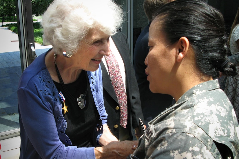 A civilian woman wearing a Silver Star talks with a soldier.