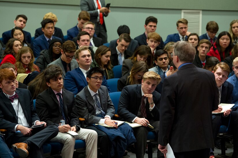 People in an auditorium listen to a man speak.