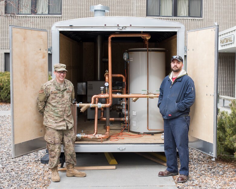 Staff Sergeant Zachary Sustar, 366th CES/HVAC, and Chris Stenson, 366th CES/HVAC stand next to the water boiler they built to help restore heating February 7, 2019 at Mountain Home Air Force Base. the boiler was built in a trailer and designed to be portable to any building on the base. (U.S. Air Force photo by Senior Airman Tyrell Hall)