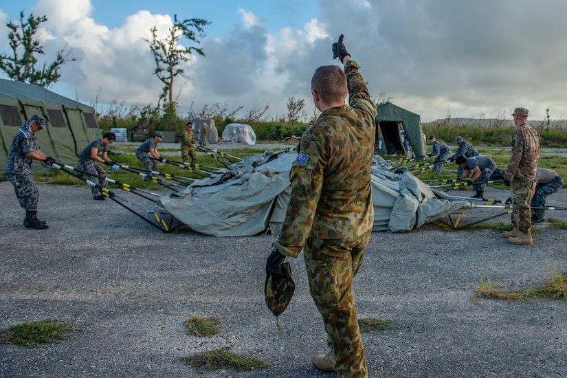 Man supervises troops setting up a tent
