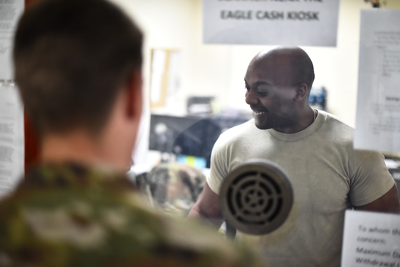 Staff Sgt. Ellis Robinson, 380th Air Expeditionary Wing customer service technician and cashier, assists a customer at Al Dhafra Air Base, United Arab Emirates, Mar. 7, 2019. Financial Management is responsible for advising, interacting and coordinating with organizations on financial matters. (U.S. Air Force photo by Senior Airman Mya M. Crosby)
