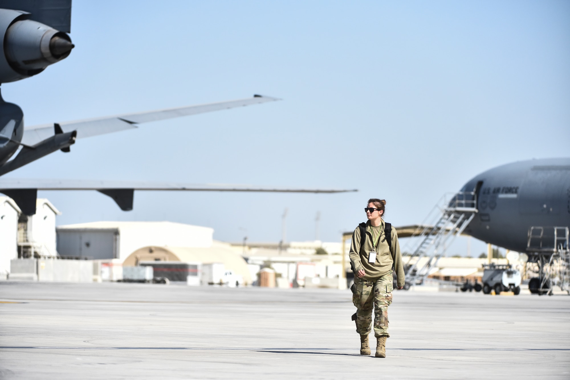 Airman 1st Class Darby Koger, 380th Expeditionary Aircraft Maintenance Squadron electronical and environmental specialist, walks past KC-10 Extenders along the flight line at Al Dhafra Air Base, United Arab Emirates, Mar. 5, 2019. E&E specialists work on the electrical systems that support the environment for personnel and passengers inside the aircraft. (U.S. Air Force photo by Senior Airman Mya M. Crosby)
