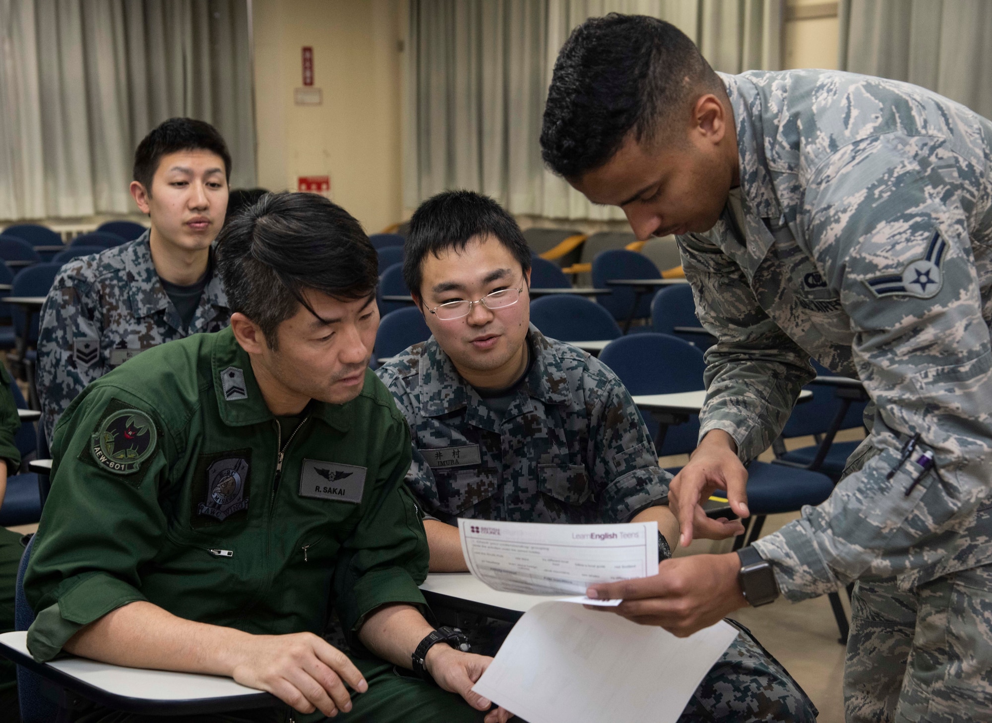 Japan Air Self-Defense Force Tech. Sgt. Ryouta Sakai, left, a 601st Squadron, Airspace Warning Control Wing operator and Airman 1st Class Taichi Imura, center, a 601st SQ AWC Wing dispatcher, receive assistance from U.S. Air Force Airman 1st Class William Raley, right, a 610th Air Control Flight weapons director technician, during an English class at Misawa Air Base, Japan, March 7, 2019. Raley said his English classes help break down language barriers between the two teams, enabling them to work more cohesively. (U.S. Air Force photo by Senior Airman Sadie Colbert)