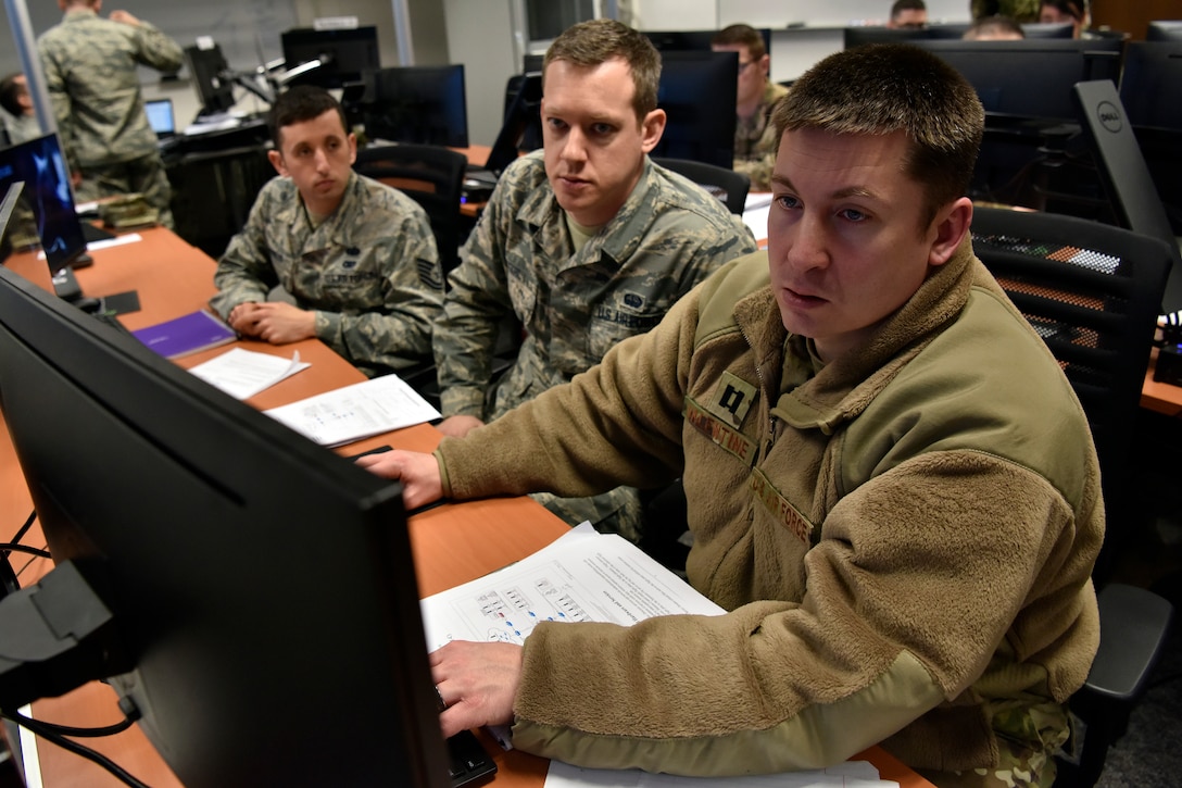 Capt. Justin Valentine (right), 100th Communication Squadron flight commander for defensive cyber operations, Tech Sgt. Michael Markus (left), 48th CS client systems technician, and Airman 1st Class Brian Stahl (center), 422nd CS noncommissioned officer in charge of cyber operations, investigate and configure firewall rules for a training scenario as part of exercise TACET VENARI.