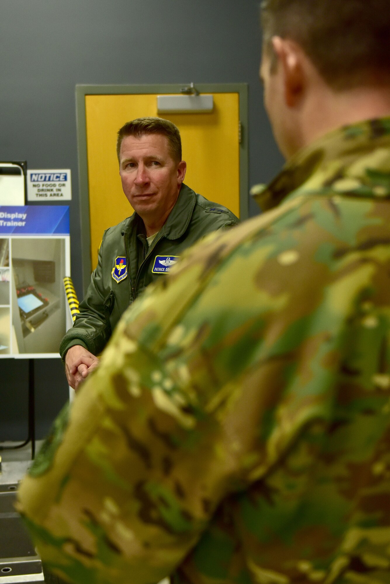 A man wearing the Air Force flight suite talks to a man wearing the operational camouflage uniform.
