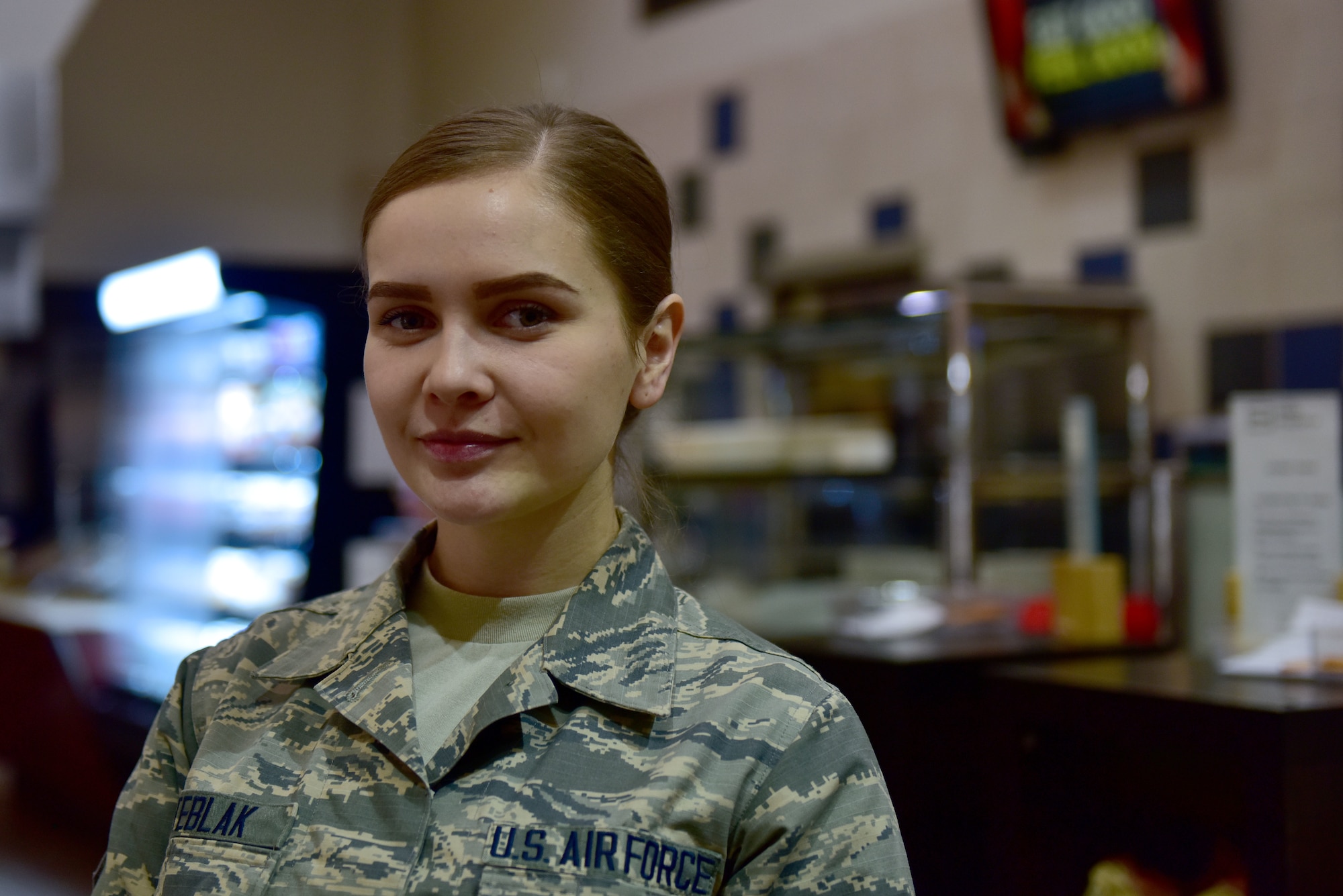 A woman in the Airman Battle Uniform smiles at the camera.