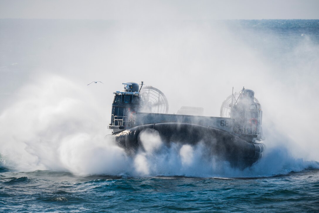 An air-cushioned landing craft moving through water.