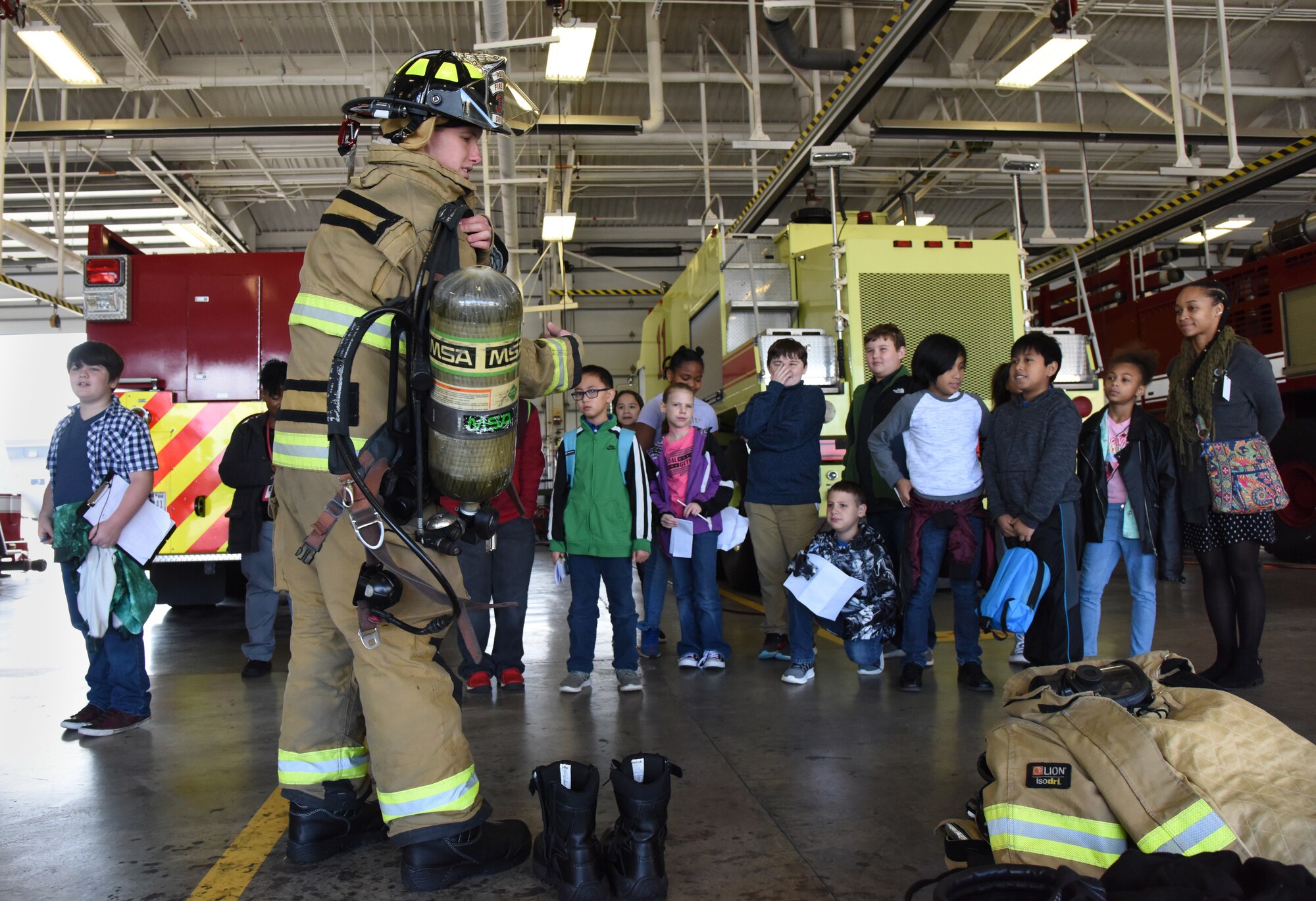 Seth Corn, 81st Infrastructure Division driver operator, demonstrates to school-aged children how to quickly get dressed in firefighter gear during Biloxi School District Career Exploration Day on Keesler Air Force Base, Mississippi, March 7, 2019. The children also toured the 334th Training Squadron air traffic control school, 335th TRS weather facility and received a demonstration from the 81st Security Forces Squadron military working dogs. (U.S. Air Force photo by Kemberly Groue)