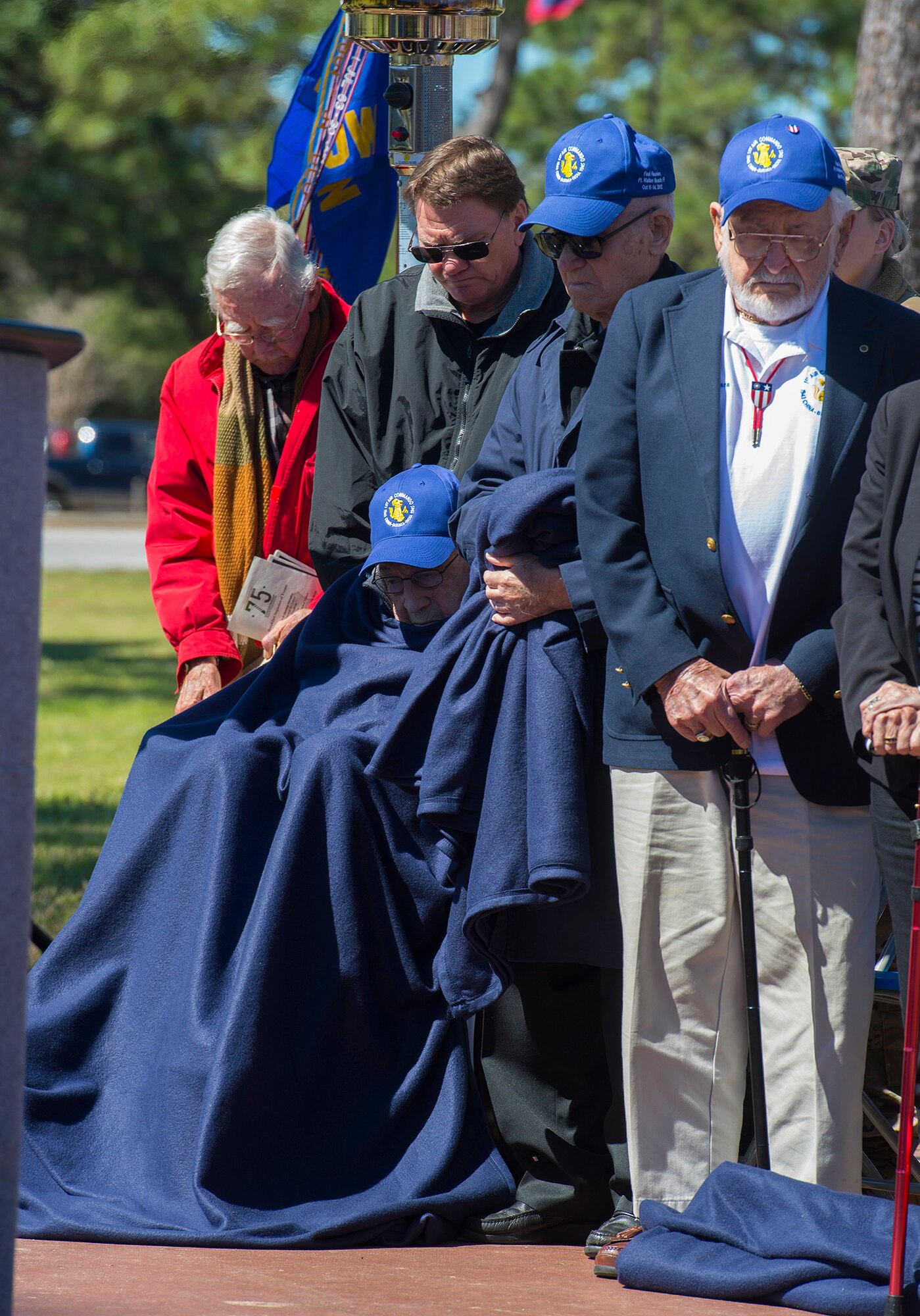 World War II veterans bow their heads during prayer