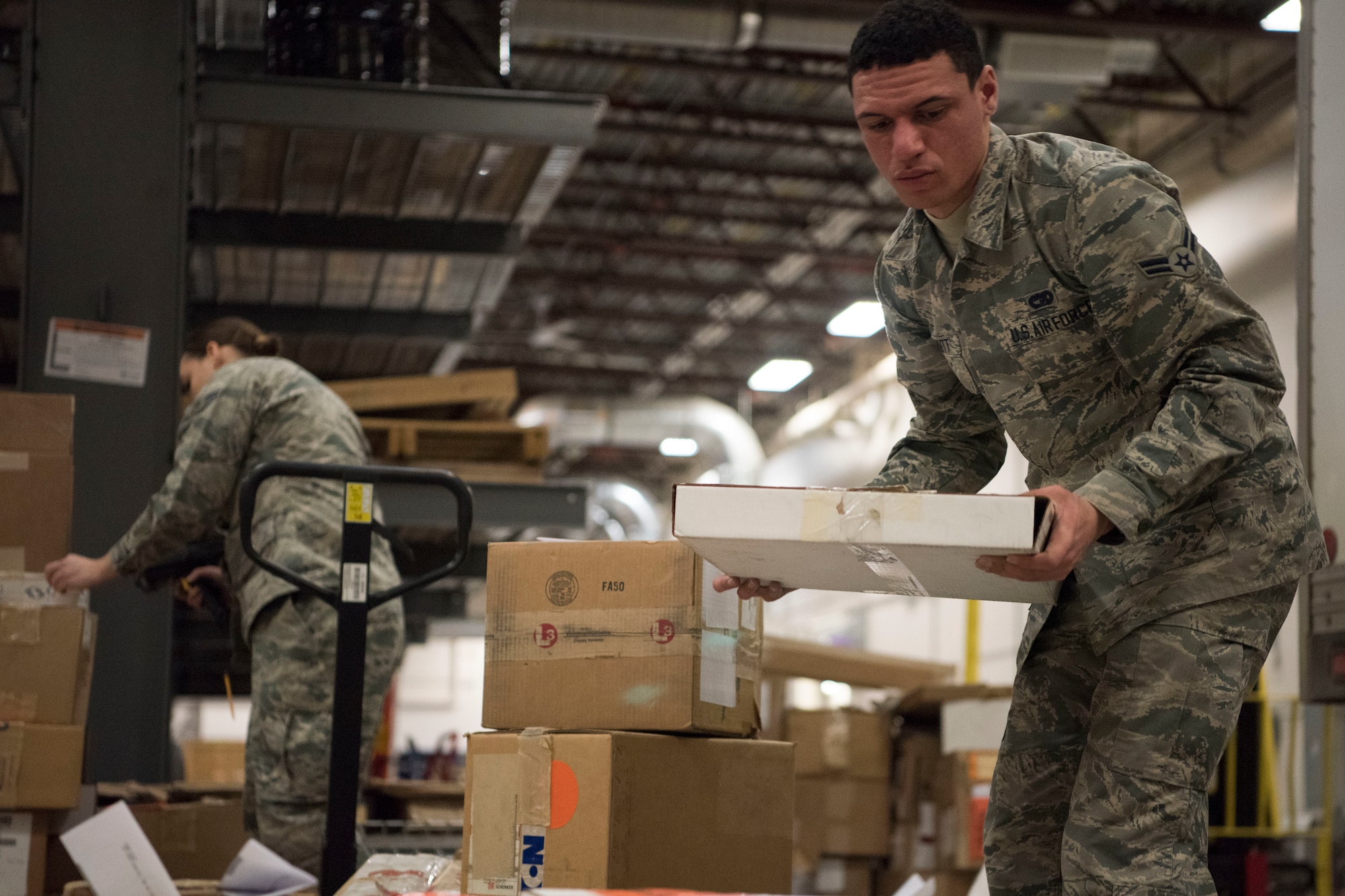 Alaska Air National Guardsmen Airman 1st Class Alan Merritt and Airman 1st Class Lauren Scanlan, both 176th Logistics Readiness Squadron ground transportation personnel, prepare a shipment of items for delivery, March 11, 2019, at Joint Base Elmendorf-Richardson, Alaska. In one of the newest total force integration associations of its kind, the 673d Logistics Readiness Squadron Materiel Management flight is conducting a complete C-17 aircraft supply turnover to the 176th LRS.