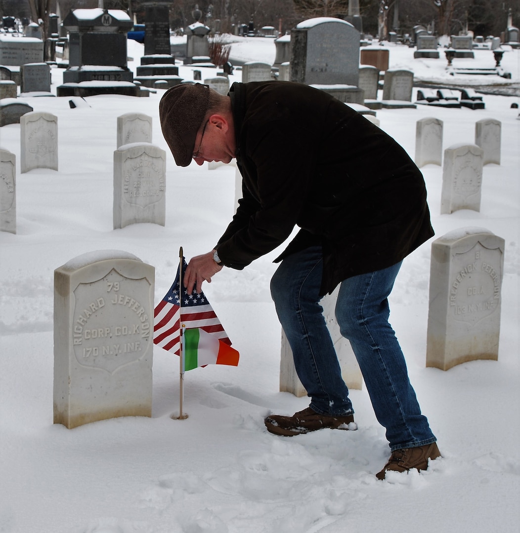 Maj. Stephen Kitchen, a member of the New York National Guard's 42nd Infantry Division headquarters, and a veteran of the 1st Battalion 69th Infantry, places an American and Irish flag on the grave of a Civil War veteran who served in the Irish Brigade at the Soldiers' Lot in Albany Rural Cemetery on March 10, 2019.