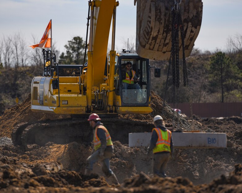 Aspen Construction workers lower a piece of cement into the ground at Joint Base Langley-Eustis, Virginia, March 7, 2019.