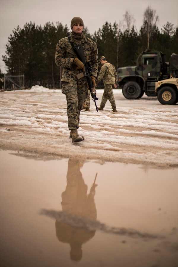 Lance Cpl. Charles Berry, a field artillery sensor support Marine with Headquarters Battery, 14th Marine Regiment, 4th Marine Division patrols a motor pool housing 14th Marines vehicles at an Adazi Training Area, Latvia, Feb. 26, 2019, during exercise Dynamic Front 19. Marines with 14th Marines are part of exercise DF19, a multinational exercise in Latvia, which includes approximately 3,820 participants from 29 nations. (U.S. Marine Corps photo by Cpl. Niles Lee)