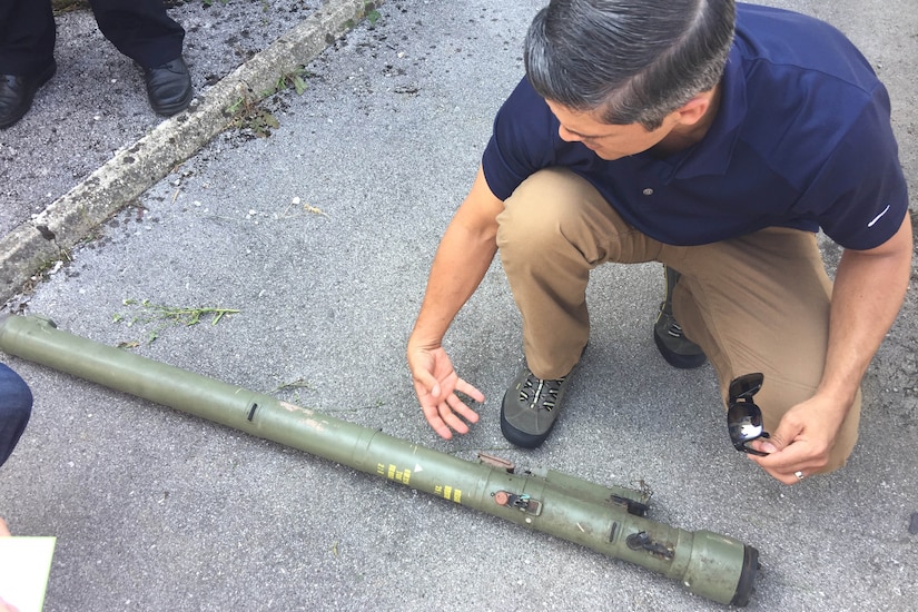 A man crouches down beside a man-portable air defense system.