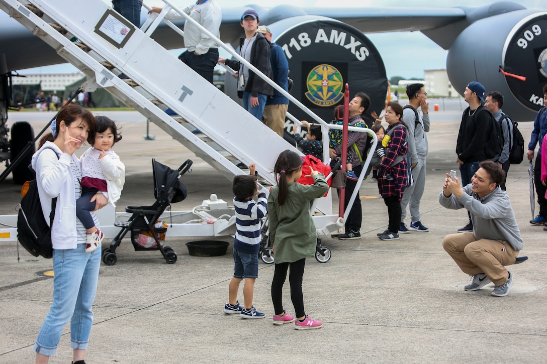 Local residents pose for a photo beside a static aircraft display at the Futenma Flight Line Fair on Marine Corps Air Station Futenma, Mar. 10, 2019. The Futenma Flight Line Fair is an annual event that includes live music, games, and food vendors for visitors to enjoy. (U.S. Marine Corps photo by Lance Cpl. Marvin E. Lopez Navarro/Released)